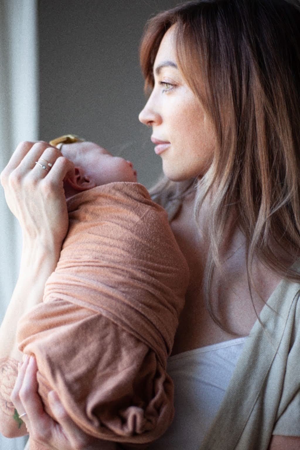 Chandra holding a newborn baby in soft light