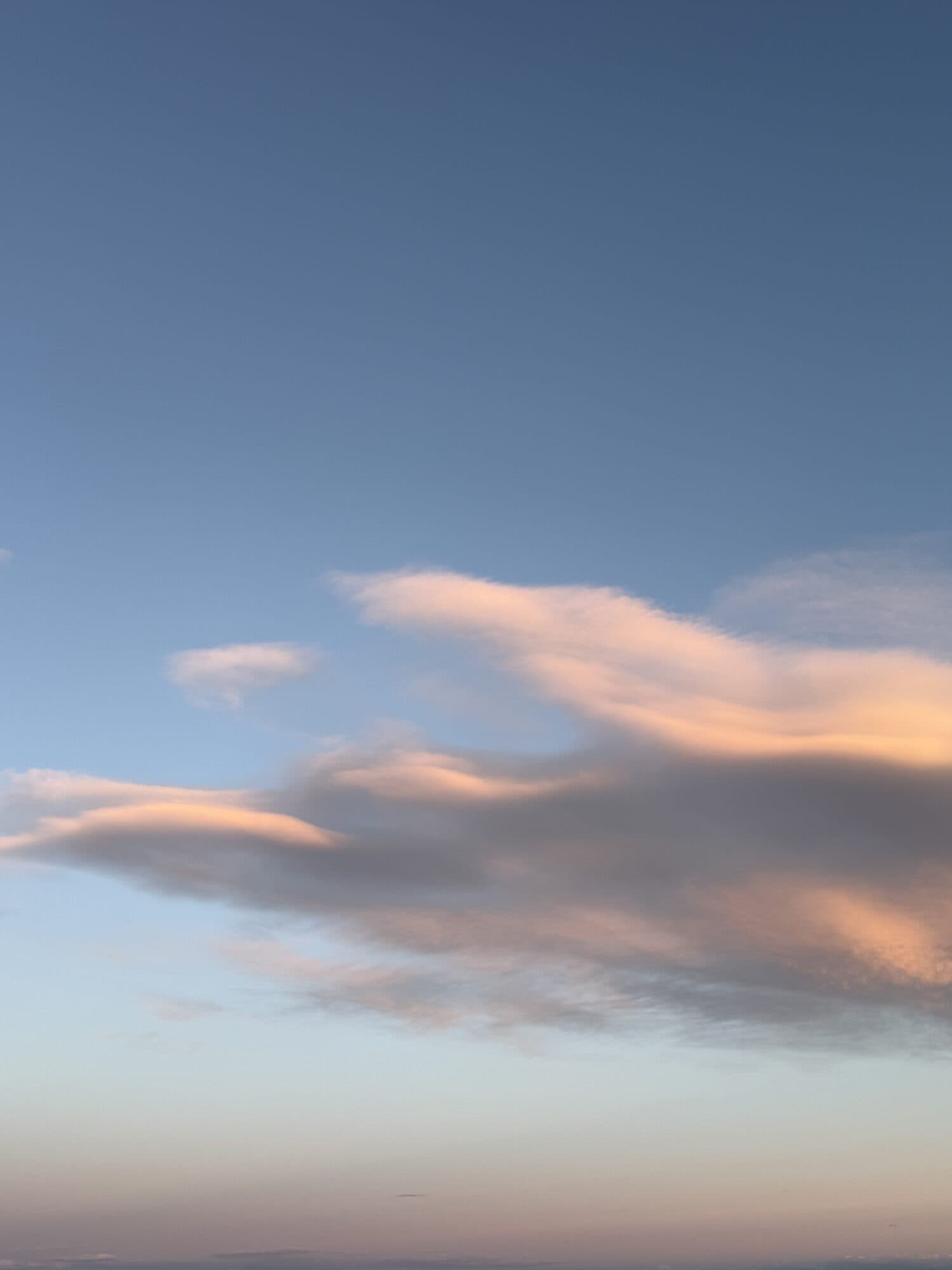 Blue sky with a single soft cloud stretching across it